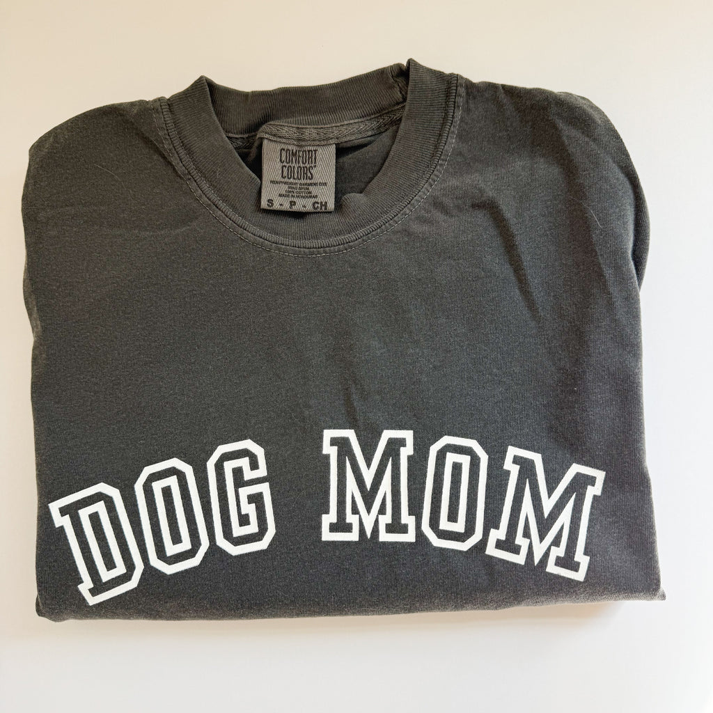 Folded dark gray sweatshirt with 'DOG MOM' text on a white background